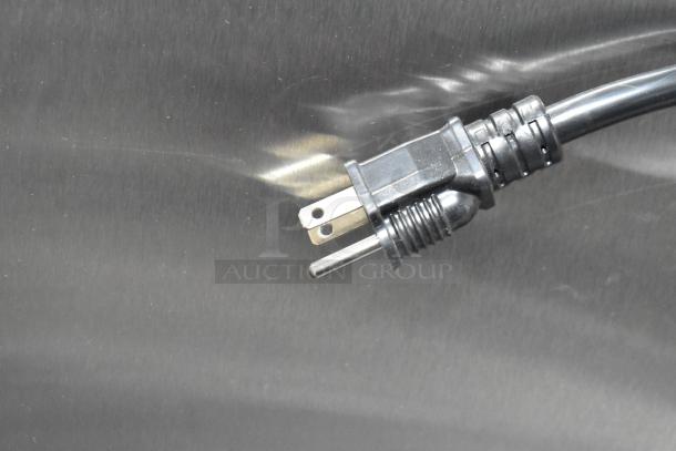 Power cord for Avantco 177HTESDC1836 heated holding cabinet, showing a three-prong plug against a metallic surface.