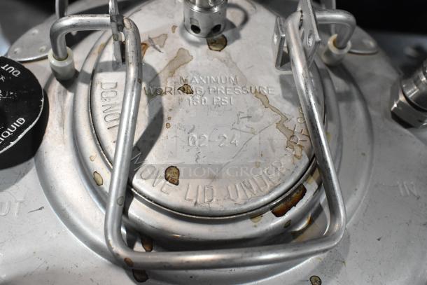 Metal homebrew keg with lid inscription "Maximum Working Pressure 130 PSI." Visible wear and minor rust stains.