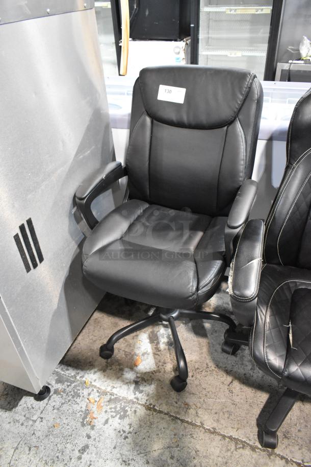 Two black office chairs on casters, padded seats, armrests, slight wear. Item tag shows "130." Ideal for home or office use.