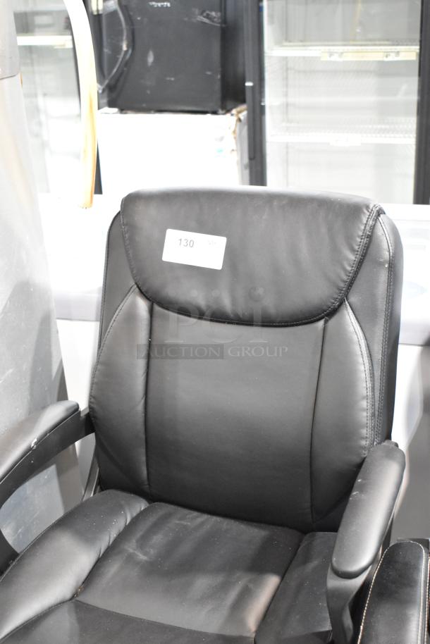 Black office chair with casters, cushioned seat, armrests, and a headrest. Label "130" on back. Good condition.