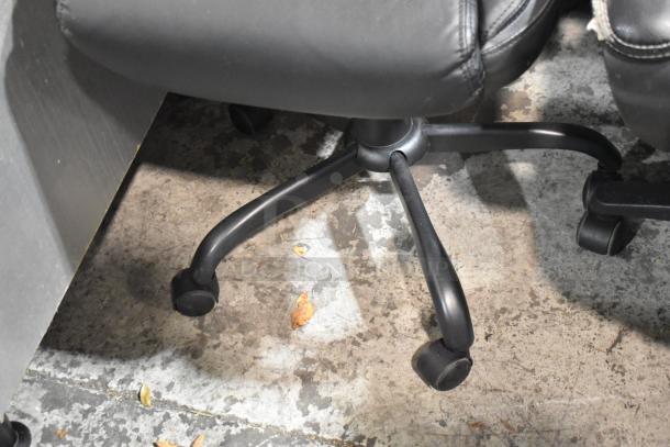 Two black office chairs on casters, leather upholstery, visible wear. Bid includes both chairs.