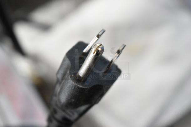 Close-up image of a power plug for the 2016 Lancer 205 Carbonator, showing prongs and part of the cable.