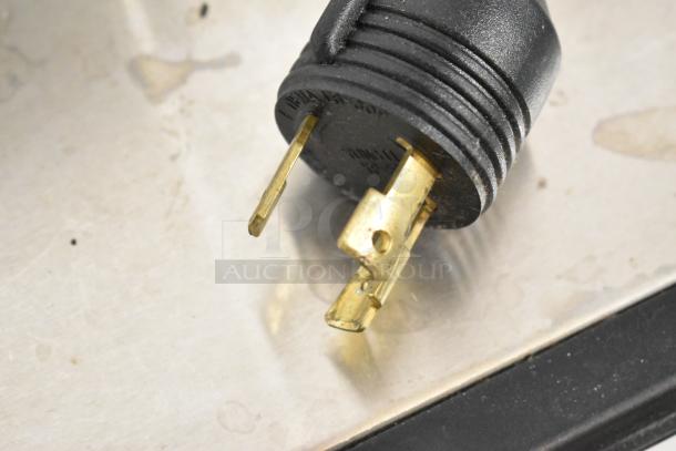 Close-up of the plug for a Schaerer Barista espresso machine, showing three gold prongs and black casing.