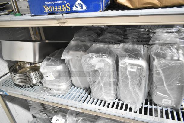 Tiered lot of various stainless steel drop-in bins, wrapped in plastic, including model 4070349. Stored on metal shelves.