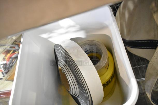 Plastic bin containing a roll of white tape and a roll of yellow caution tape, part of a mixed auction lot.