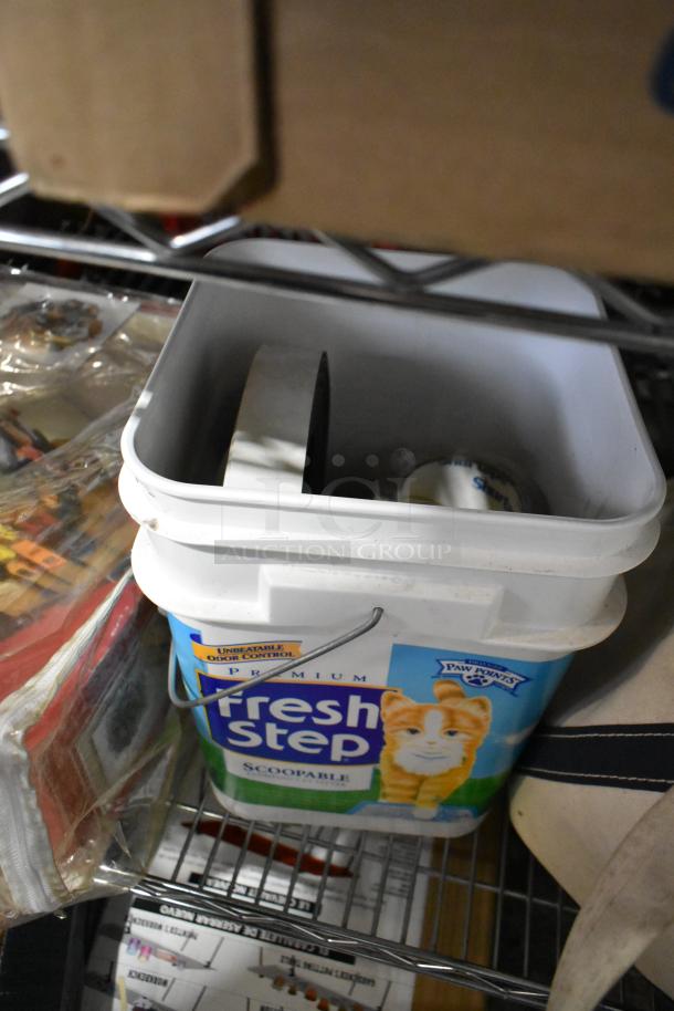 Auction tier lot featuring ladder dolly, rolling tool organizer, toilet pipe extender, stored in a Fresh Step container.