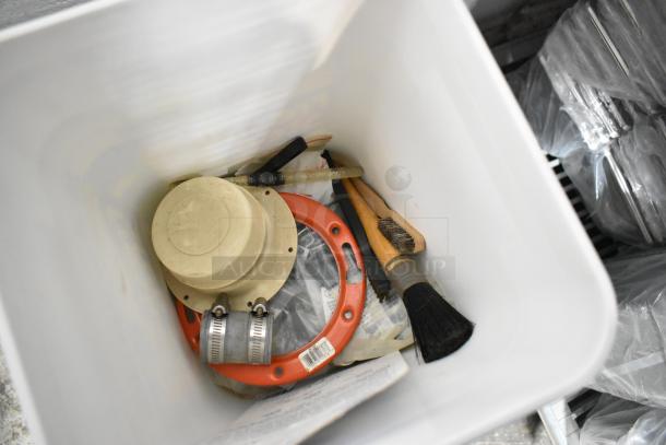 Lot of assorted tools including a toilet pipe extender, brushes, and hose clamps in a white container. Various conditions.