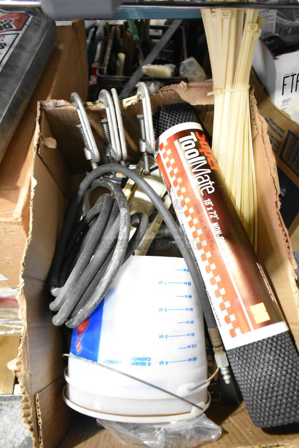 A mixed lot including Super ToolMate sheeting, measuring bucket, cables, clamps, and zip ties, all in a cardboard box.