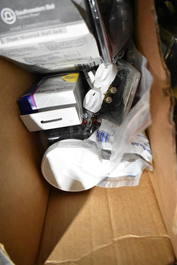 Box containing a variety of items like file folders, plastic sheeting, a doorknob, and outlet covers in new condition.