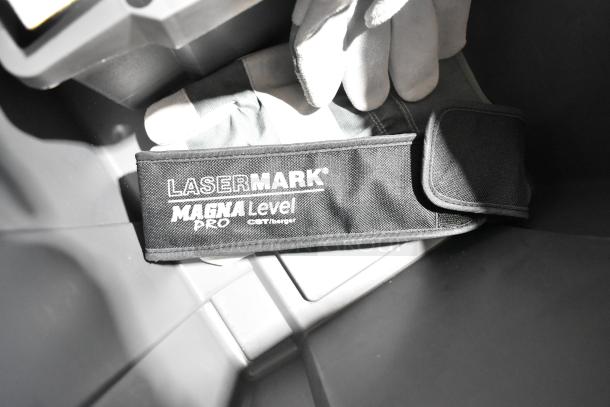 Lasermark Magna Level Pro device in a gray Poly tool box, with gloves. Features Lasermark branding on strap.