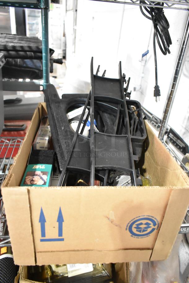 Cardboard box containing a variety of items including a Tru Rubber extension cord and gray poly tool box, on a metal shelf.
