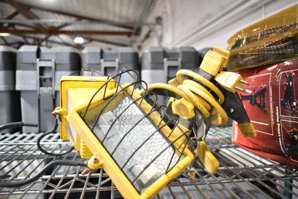 Auction lot with SM2262 Magnetic Base Worklight, stretch net, and jack stands on a metal shelf. Items appear used.