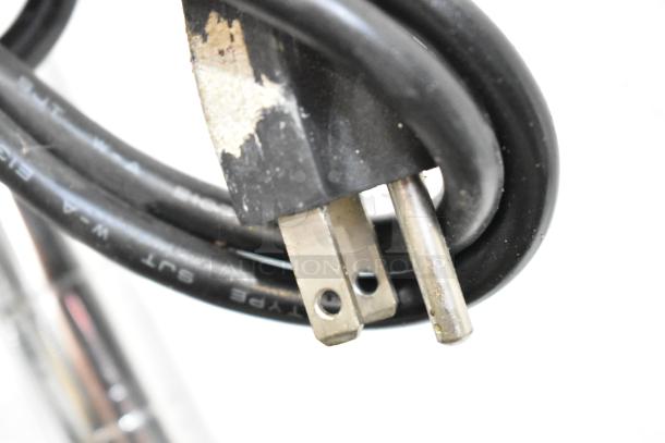 Close-up of a two-prong electrical plug attached to a black cable with worn insulation, part of the auction tier lot.