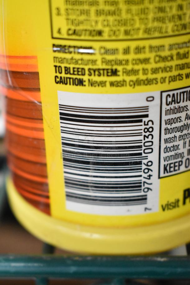 Barcode and caution label on a yellow container, part of an auction lot including a window air conditioner, drum liners, knobset, brake fluid.