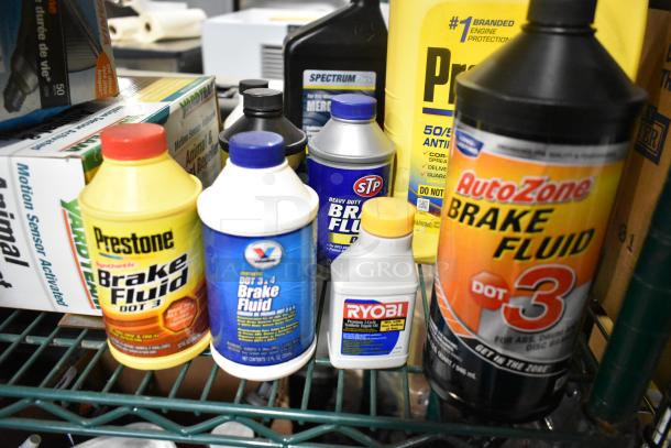 Lot of automotive supplies including Prestone, STP, AutoZone brake fluids, Ryobi lubricant on shelf. Mixed condition.