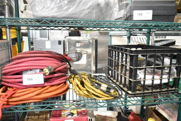 Multi-item lot including red and yellow extension cords, a Security Plus System 1000 alarm, and miscellaneous items in a crate.