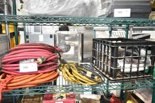 Multi-item lot including red and yellow extension cords, a Security Plus System 1000 alarm, and miscellaneous items in a crate.