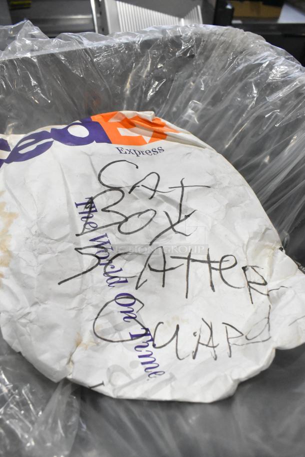 FedEx Express package with handwritten "Cat Box" text in black marker, crumpled and placed in a plastic bag.