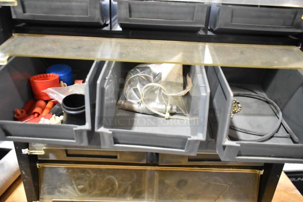 Poly hardware holder with bins, containing assorted small parts and tools. Overall good condition with visible storage and organization capabilities.