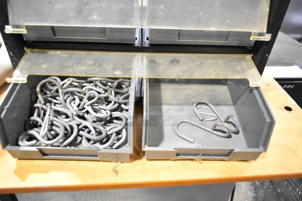 Poly hardware holder with gray bins containing metal hooks. Dual-compartment design. Some wear visible on clear lids.