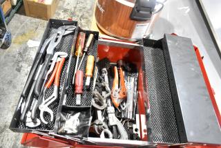 Red metal tool box with assorted tools, including pliers and screwdrivers, in good condition.