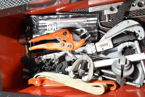 Red metal tool box filled with various tools, including Ridgid and Craftsman brands. Contains pliers, wrenches, and more.