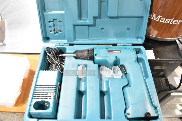 Makita electric drill in blue hard case, includes charger and accessories, well-maintained, ideal for professional use.