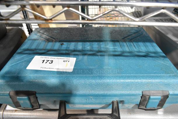 Makita electric drill in blue hard case, label reads "173 QTY 1, PCIAuctions.com," sturdy condition.