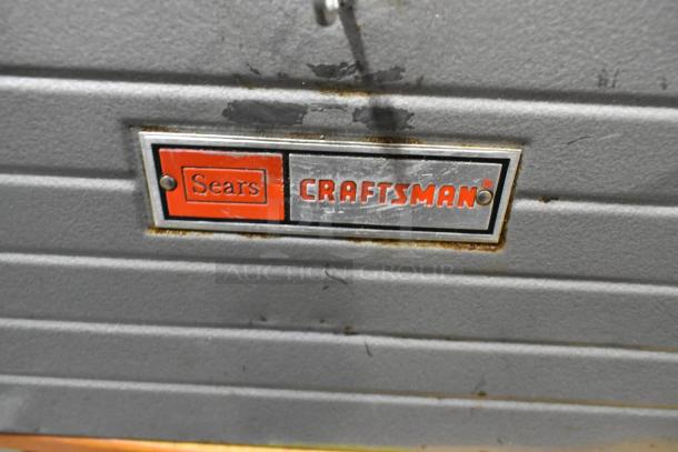 Craftsman gray metal tool box with Sears Craftsman logo, showing wear; includes contents.