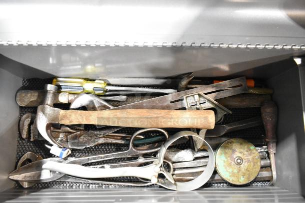 Craftsman gray metal tool box with assorted tools inside, including hammers, screwdrivers, and pliers. Visible wear on tools.