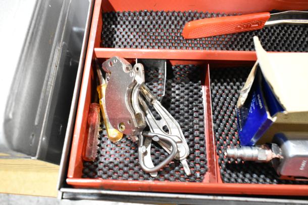 Craftsman gray metal tool box interior with assorted tools, red handle screwdriver, carabiner clip, and a labeled box.