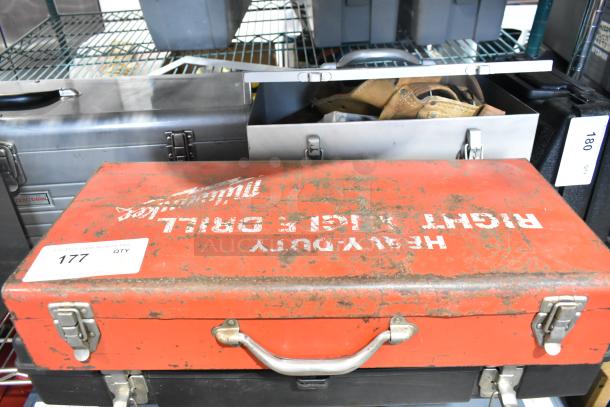 Milwaukee electric right angle drill in worn red metal tool box, labeled "Heavy Duty." Box shows signs of wear.