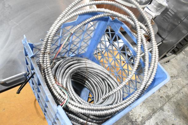 Auction lot with coiled metal wires in a blue crate. Includes wires, gloves, and poly boxes. Items appear in good condition.