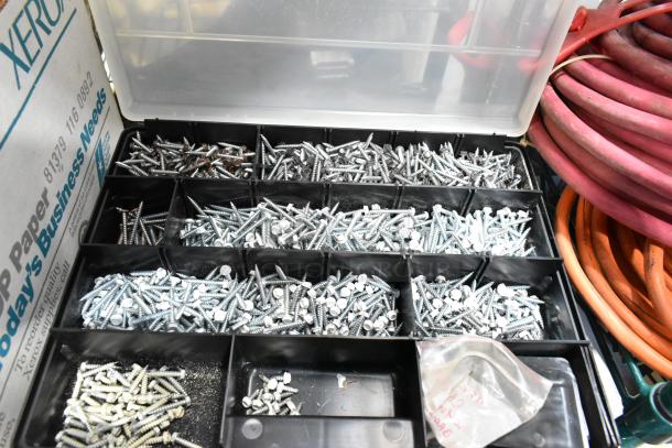 A tiered lot of various screws sorted in a black plastic organizer, alongside visible red and orange wires.