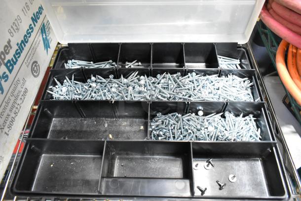 Tiered organizer with metal screws, divided sections, and additional visible inventory boxes, indicating mixed-condition hardware.