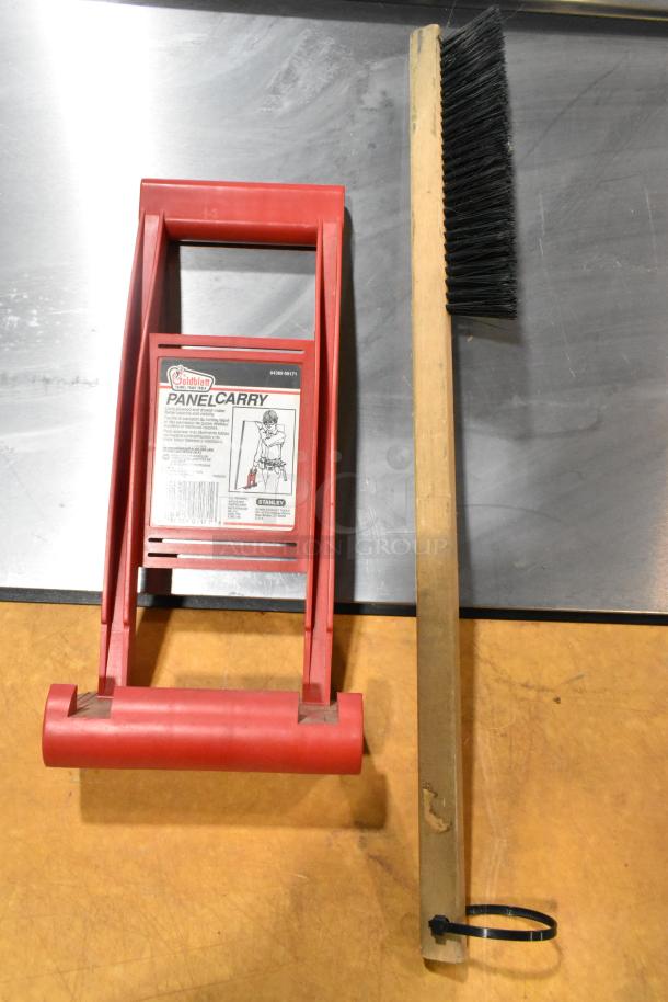 Auction lot including a red Goldblatt Panel Carry with visible label and a wooden-handled brush.