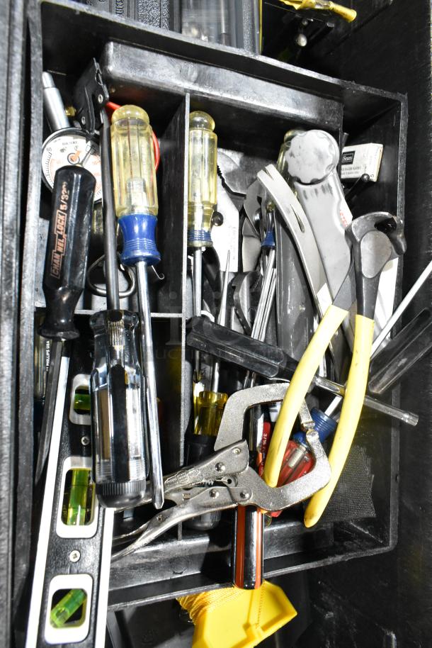 Gray poly tool box filled with various tools including screwdrivers, pliers, and measuring tape. Items show signs of use.