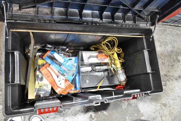 Black tool box filled with various tools, including sealed packages, electrical cords, and a hand light. Well-organized interior.
