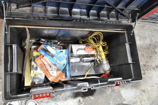 Black tool box filled with various tools, including sealed packages, electrical cords, and a hand light. Well-organized interior.