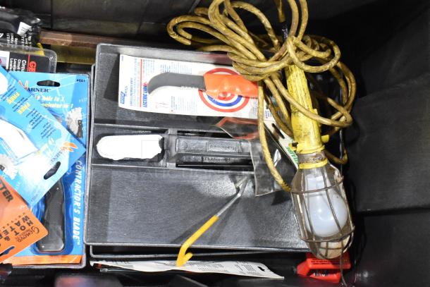 Tool box with assorted tools including a utility cutter, light bulb with cage, rope, and packages. Good condition.