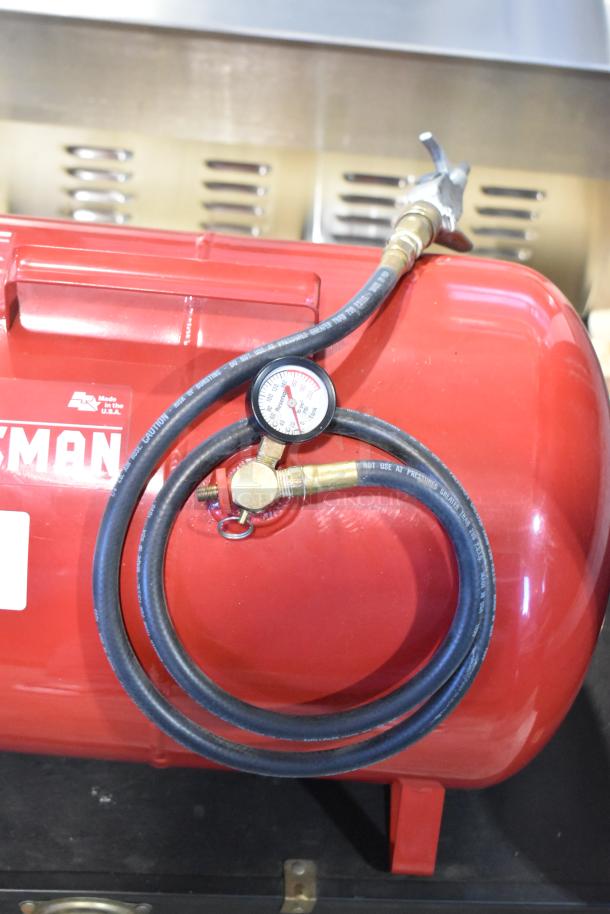 Craftsman 919-15209 air compressor, red, with attached hose and pressure gauge; "Made in the U.S.A." label visible.