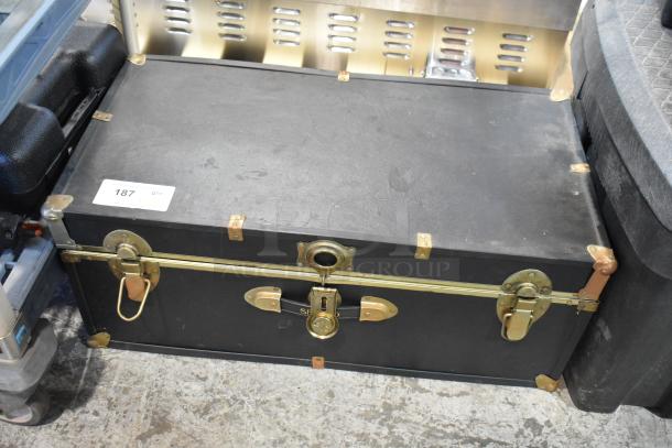 Black trunk in good condition with brass hardware, includes a fire blanket. Numbered tag "187" visible.