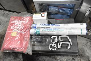 Red emergency fire blanket in packaging, ladder dolly box, adhesive carpet and floor protection rolls, and metal brackets on trunk.
