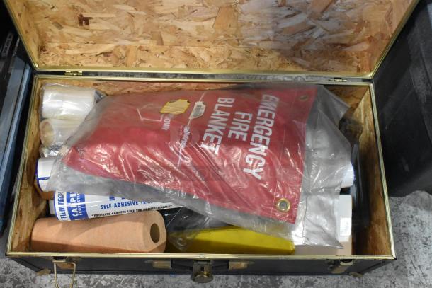 Vintage-style trunk with contents including an emergency fire blanket, self-adhesive film, and paper roll. Appears well-maintained.