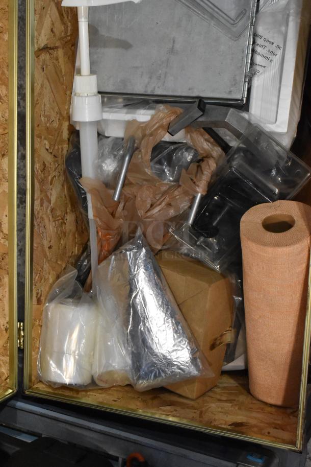 Trunk with assorted contents including a silver fire blanket, plastic wrap, and cardboard box. Items in new condition.