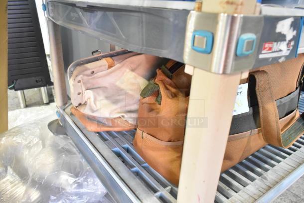 Two various bags on a shelf, containing trowels. Bags in used condition, one tan and one brown, no visible tags or labels.