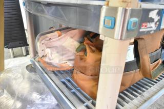 Two various bags on a shelf, containing trowels. Bags in used condition, one tan and one brown, no visible tags or labels.