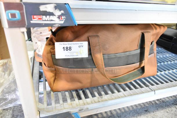 Two brown bags with black accents, containing trowels, placed on a metal shelf. Auction tag 188 reads "QTY x2".