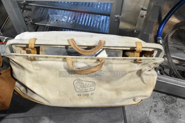 Two bags containing various tools, including trowels. The larger bag is marked "Goldblatt, 09122, HT" and shows wear.