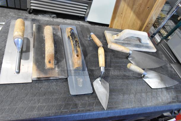 Two assorted bags with various trowels and plastering tools, wooden handles, used condition. Auction for two times the bid.